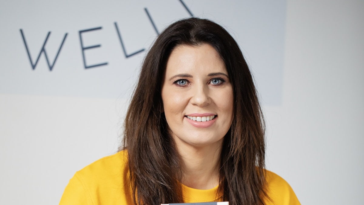 Woman with dark hair smiling, wearing yellow shirt.